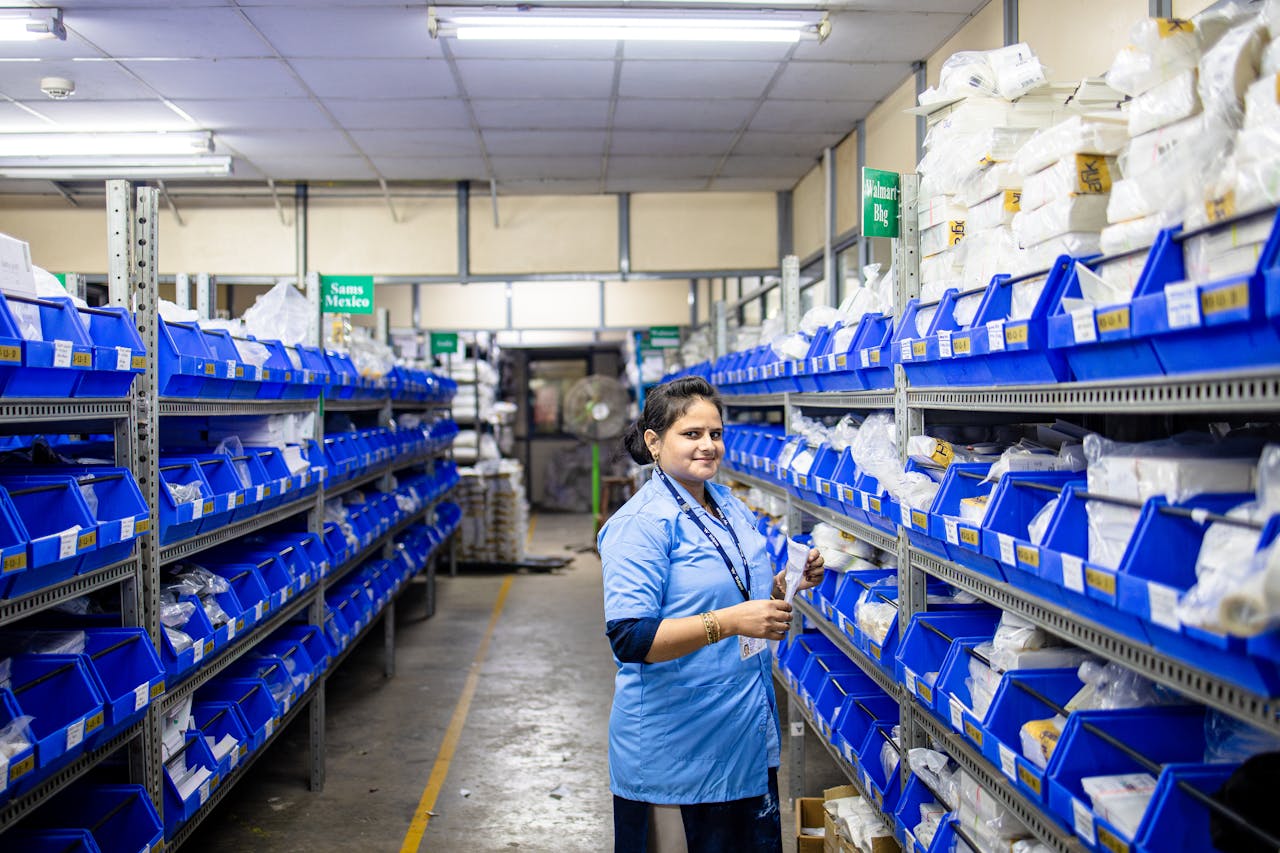 why-choose-us Female worker organizing inventory in a warehouse with blue bins and bright lighting.