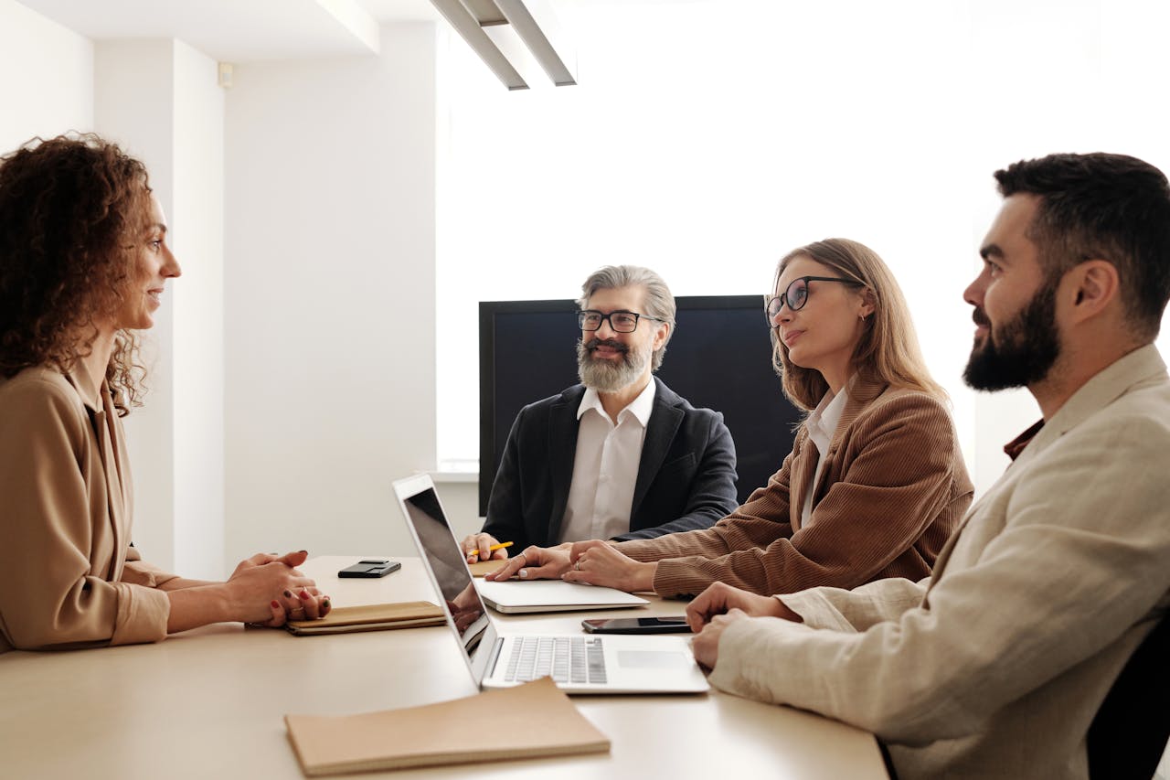 Group of professionals in a business meeting discussing strategies around a table in an office setting.
